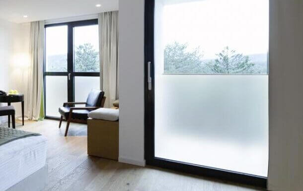 Belle chambre d'hôtel avec deux grandes baies vitrées dont la partie basse de la vitre est recouverte de films adhésifs occultants.