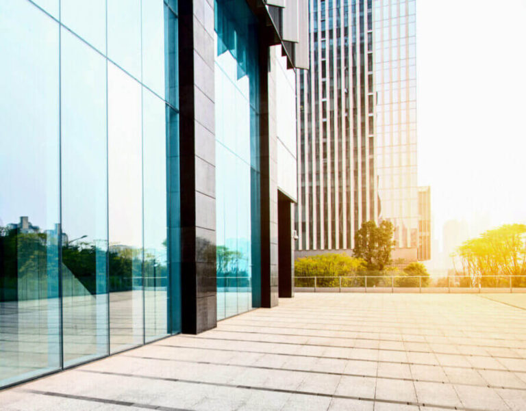 Façade du rez-de-chaussée d'un bâtiment vitré sous un soleil intense.