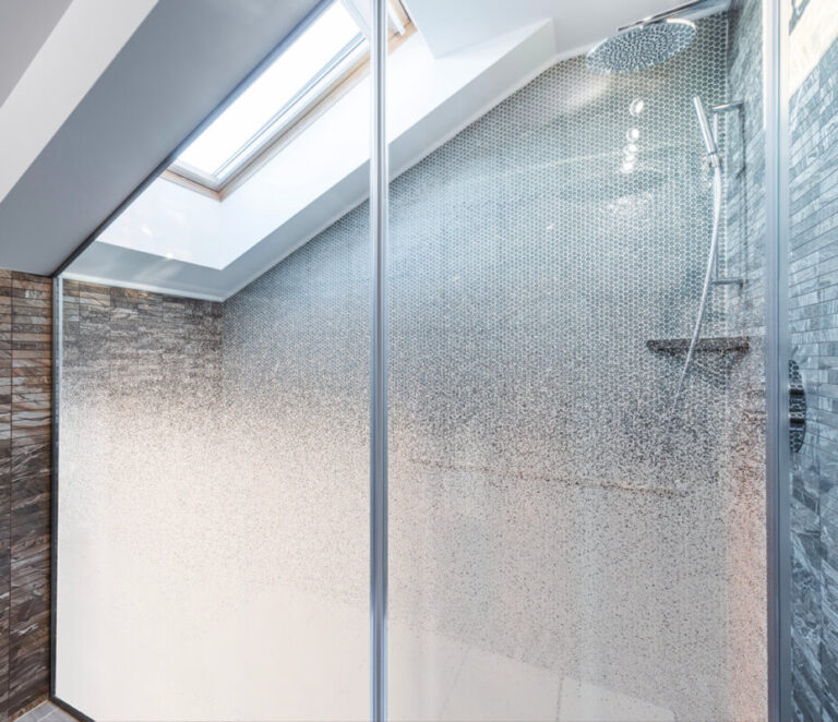 Gros plan sur une grande douche à l'italienne dont la paroi vitrée est recouverte d'un film de confidentialité avec une texture de grain dégradée.
