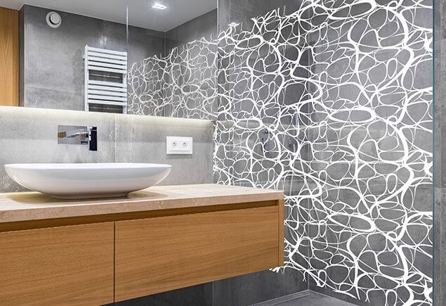 Salle de bains moderne avec une paroi de douche recouverte d’un film décoratif à lignes blanches organiques.